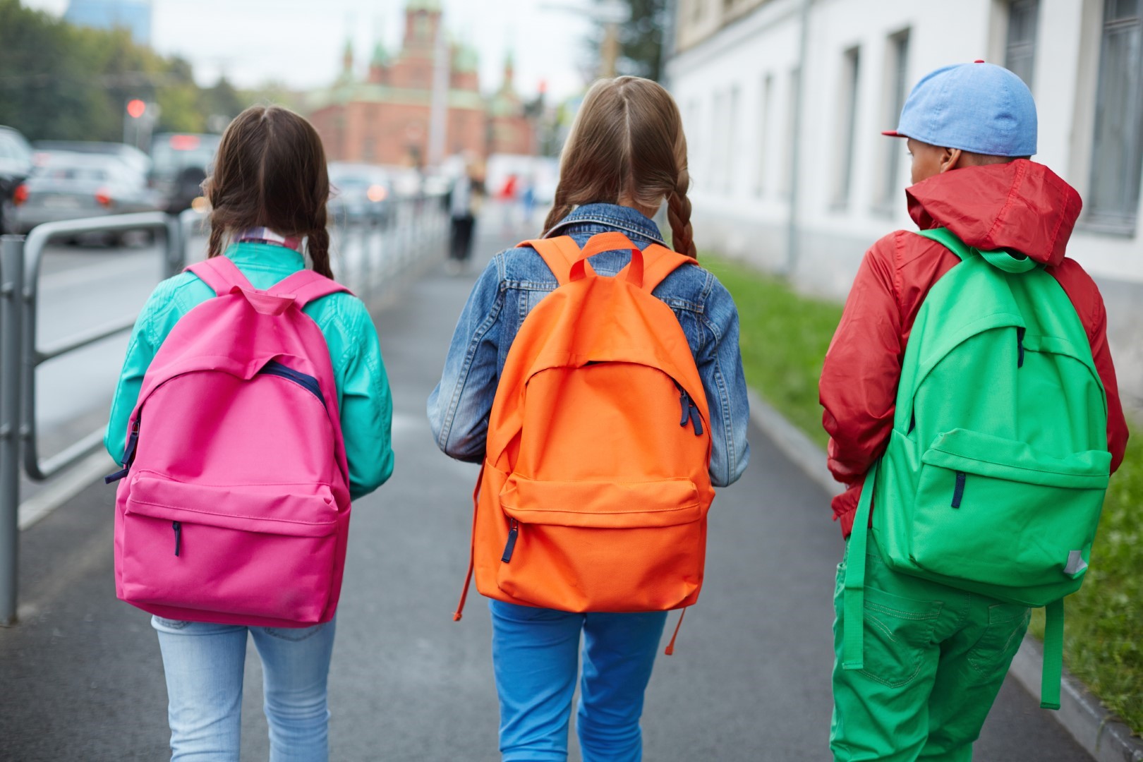 Three children walking carrying brightly coloured backpacks
