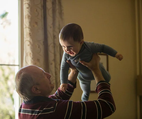 Older man holding baby boy in the air
