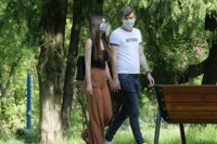 young couple walking in park wearing face masks