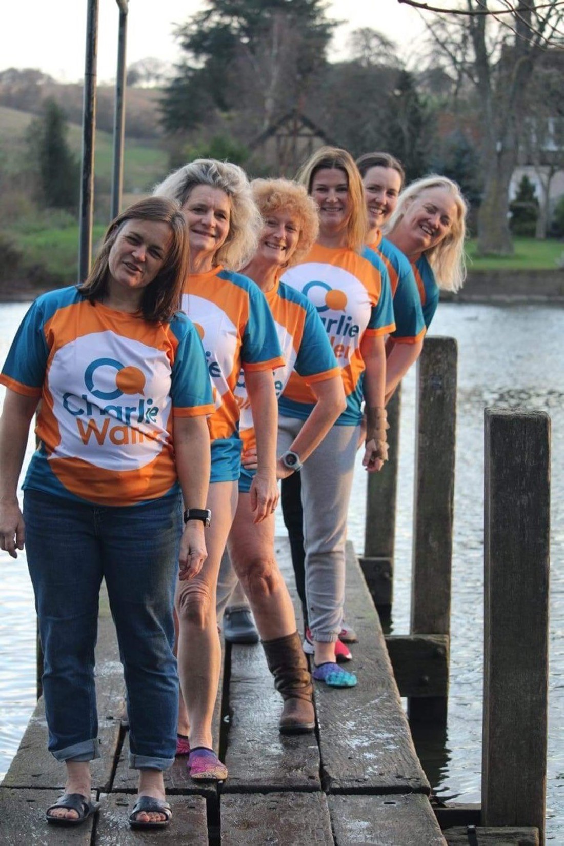 six women in Charlie Waller orange and blue t-shirts standing on river pontoon