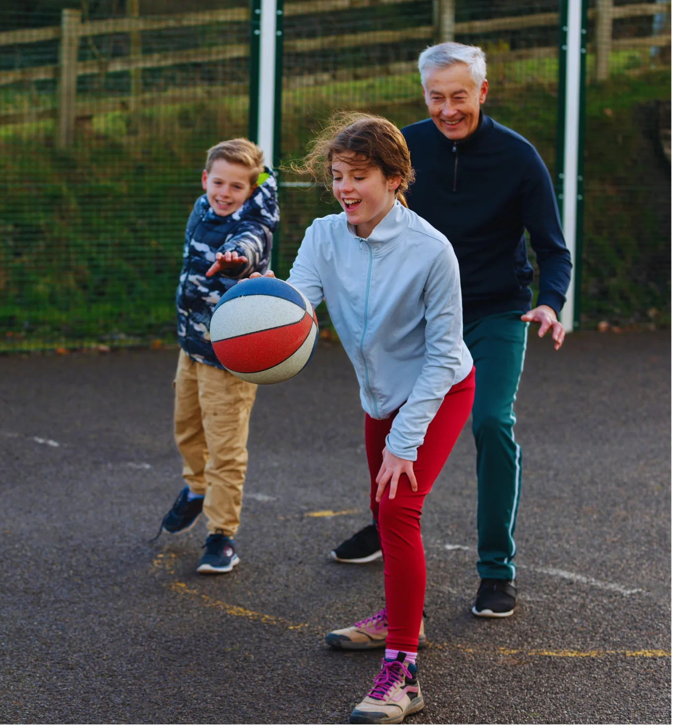 two white children and a dad playing basketball outside