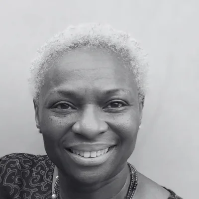 Faramade, a Black woman with short hair smiling at the camera. Faramade, a Black woman with short hair smiling at the camera.