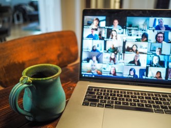 Hot drink next to a laptop with group video call 