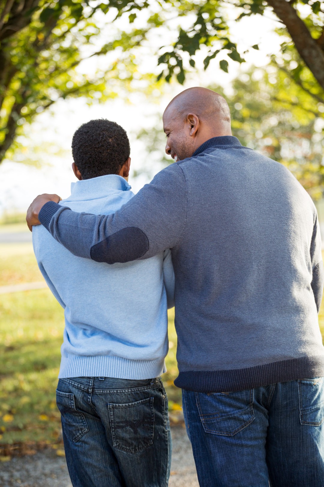 Adult with his arm around young person, backs to camera