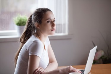 Girl looking away from her laptop 