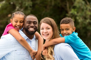 Family smiling with children on parent's backs 