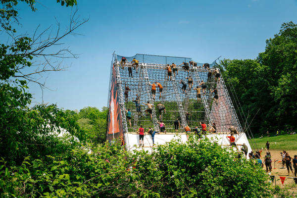 Image of people climbing over an obstacle on the tough mudder course