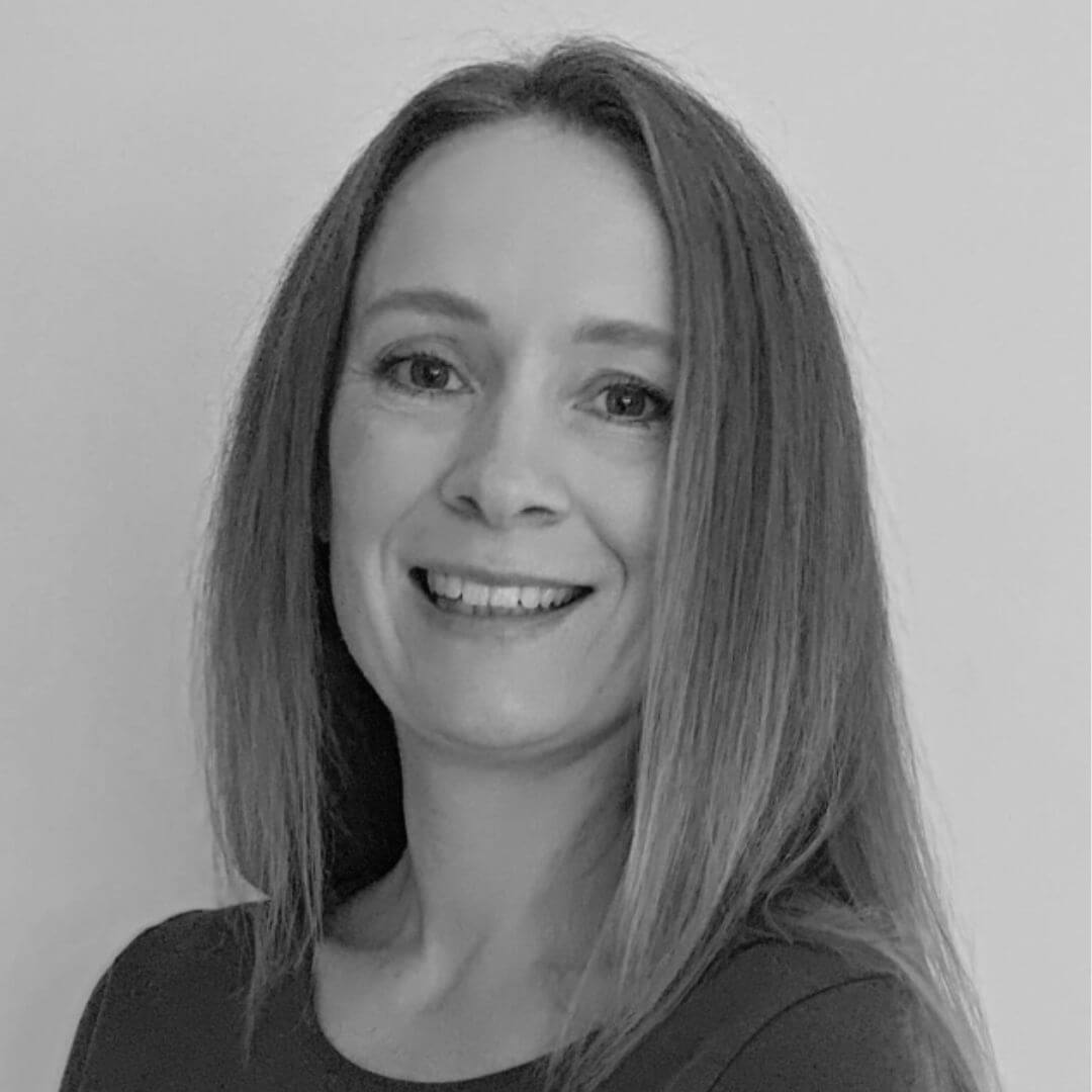 A black and white image of Michelle, a woman with medium length hair smiling at the camera.