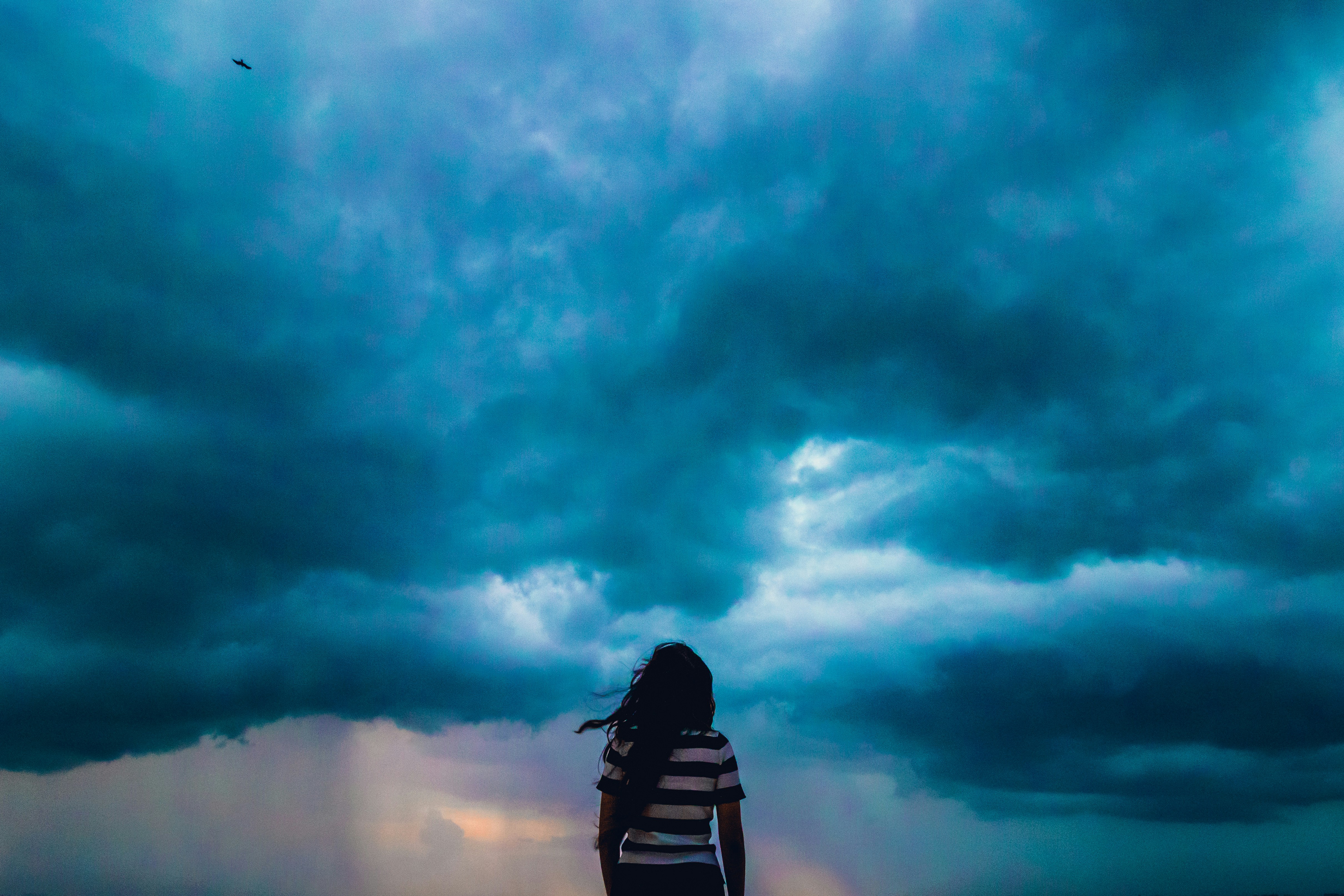 Girl standing under stormy clouds