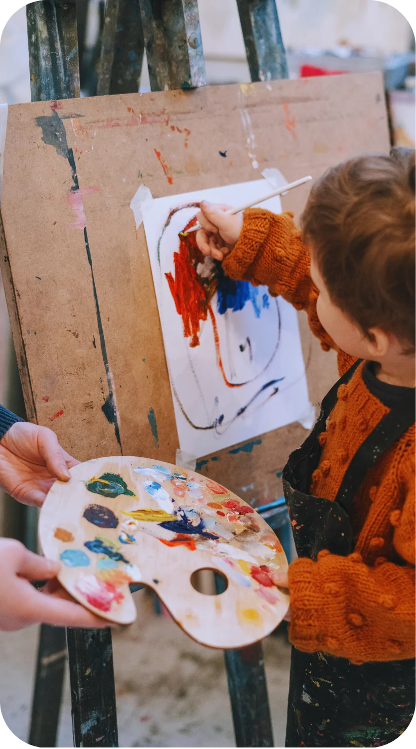 young white boy painting on an easel 