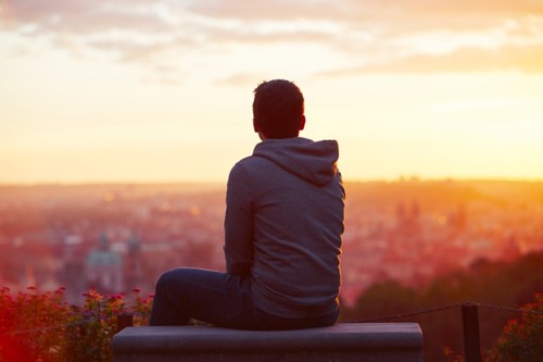 Male sitting looking at a sunset
