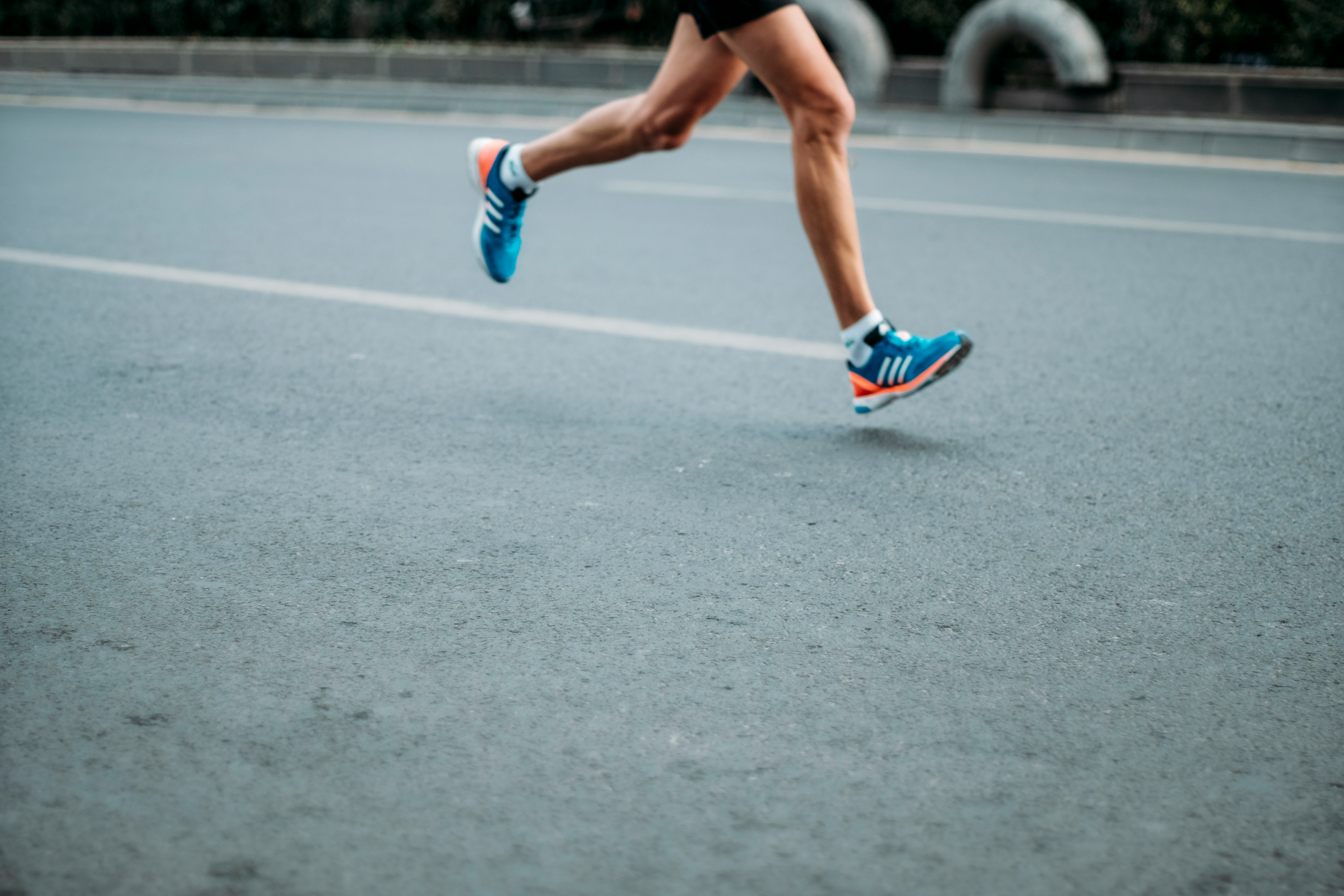 One person running, shot of legs and feet on road