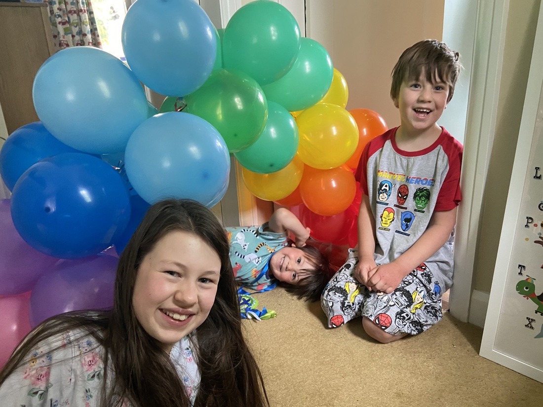 Children smiling at camera with balloons in the background