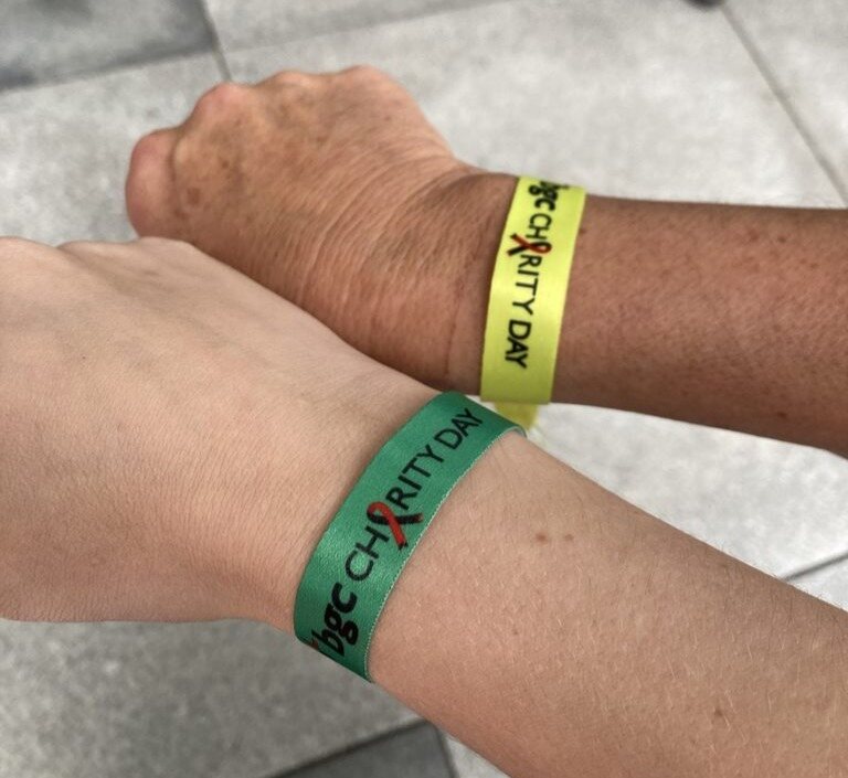 Two people's hands wearing branded wristbands
