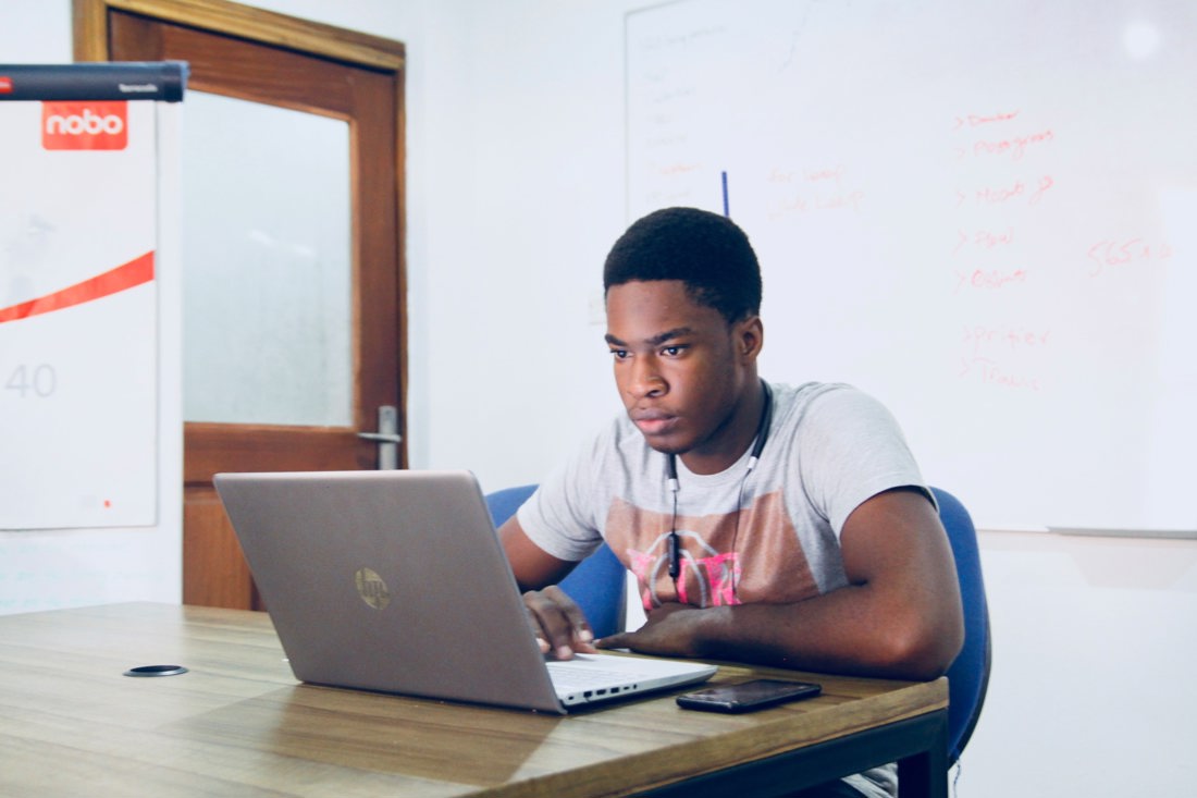 Black boy at desk looking at laptop
