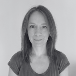 A black and white image of Michelle, a woman with medium length hair smiling at the camera.