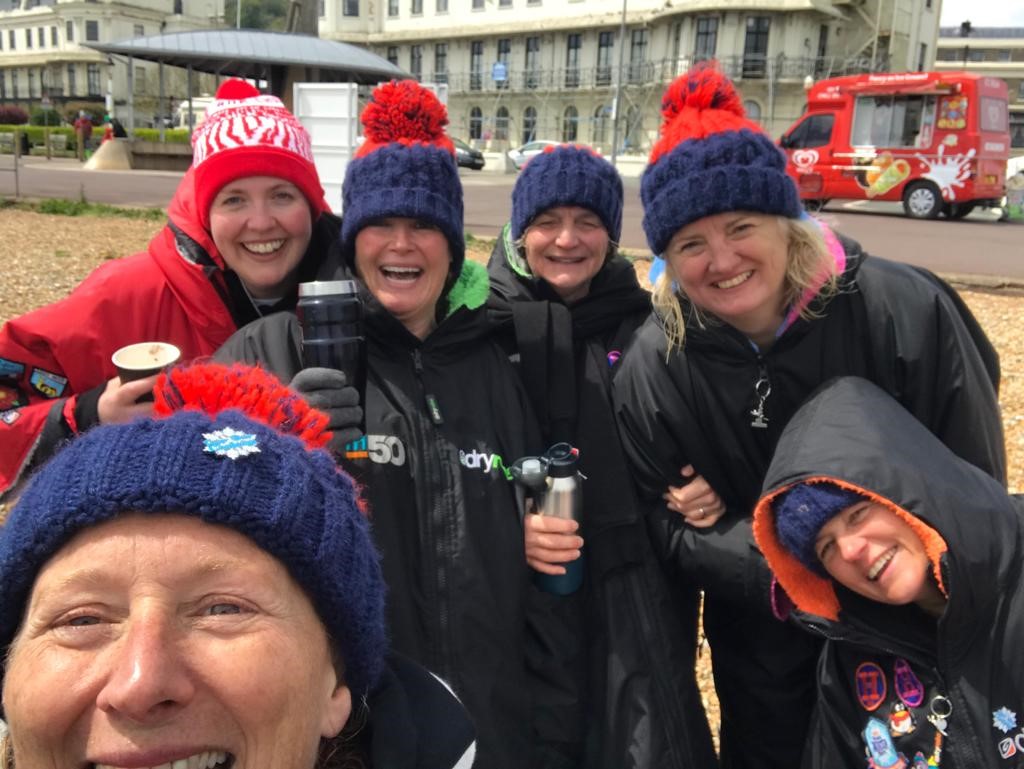 happy women in big coats and woolly hats holding thermos flasks
