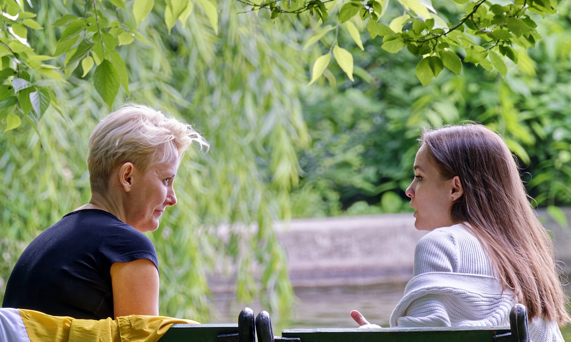 Older person talking to younger person outside under trees