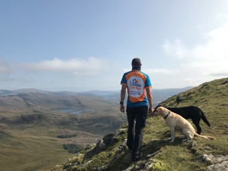 Man looking out over valley with 2 dogs