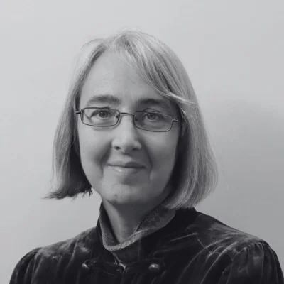 Tracey, a white woman with white hair and glasses. Tracey, a white woman with white hair and glasses.