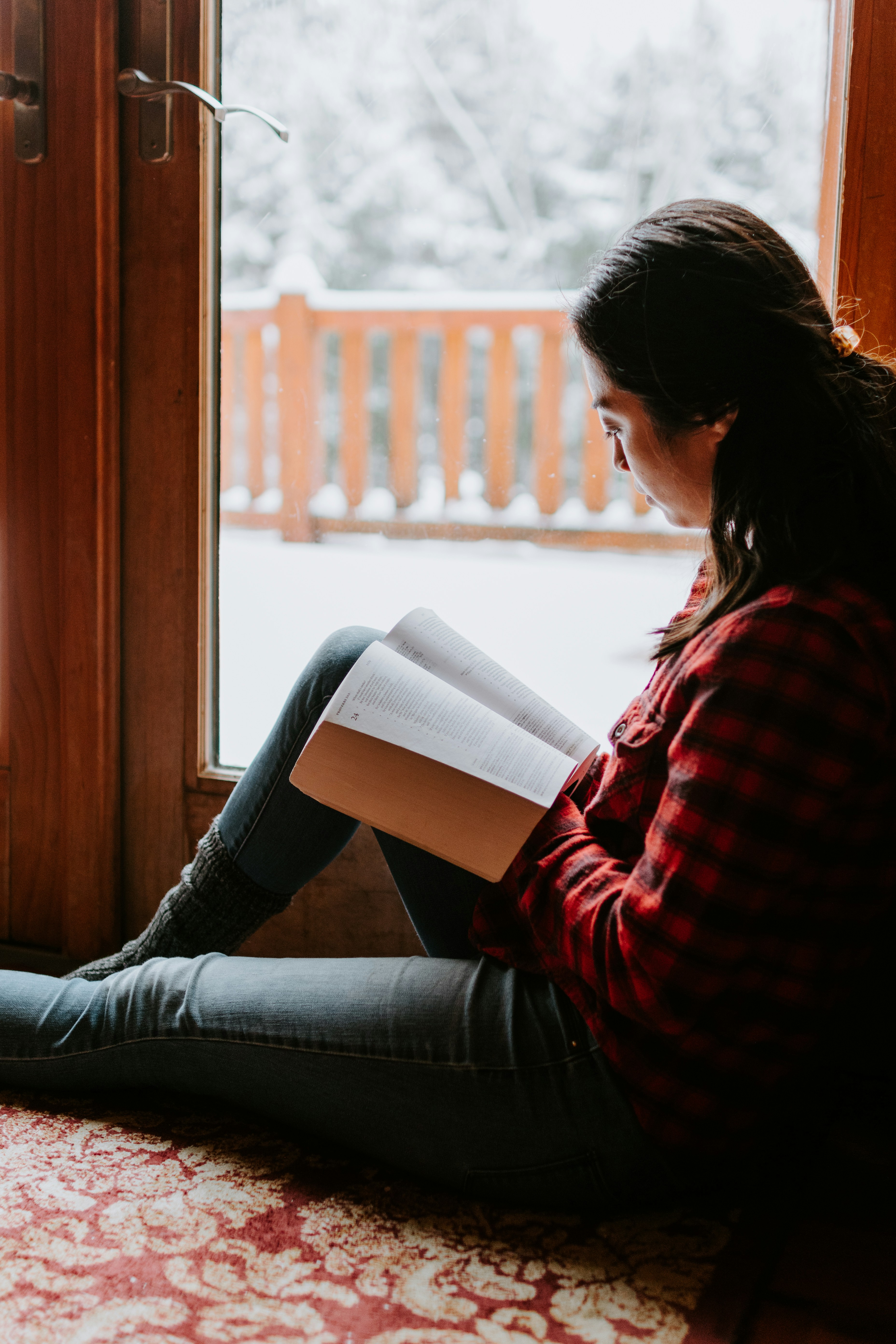 Person reading in window seat with snow outside